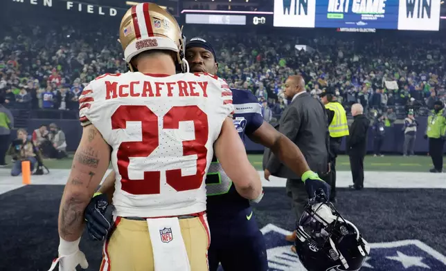 San Francisco 49ers running back Christian McCaffrey (23) greets Seattle Seahawks running back Kenneth Walker III (9) after an NFL football divisional playoff game Saturday, Jan. 17, 2026, in Seattle. (AP Photo/John Froschauer)