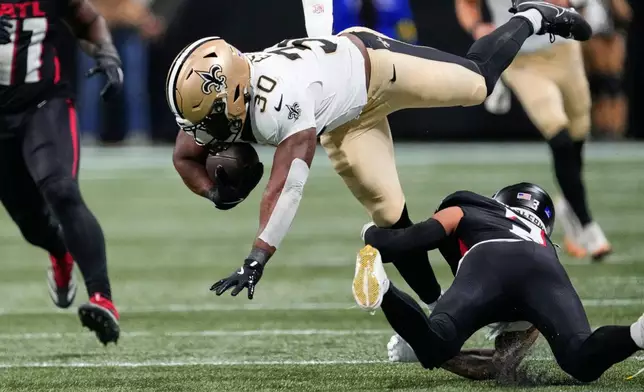 New Orleans Saints running back Audric Estime (30) is tripped up by Atlanta Falcons safety Jessie Bates III (3) in the first half of an NFL football game, Sunday, Jan. 4, 2026, in Atlanta. (AP Photo/Brynn Anderson)