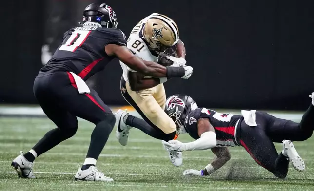 New Orleans Saints wide receiver Kevin Austin Jr. (81) carries between Atlanta Falcons cornerback Dee Alford (20) and linebacker Divine Deablo (0) in the first half of an NFL football game, Sunday, Jan. 4, 2026, in Atlanta. (AP Photo/Brynn Anderson)