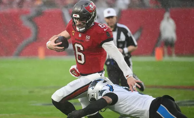 Tampa Bay Buccaneers quarterback Baker Mayfield (6) runs around the tackle attempt from Carolina Panthers safety Tre'von Moehrig during the first half of an NFL football game Saturday, Jan. 3, 2026, in Tampa, Fla. (AP Photo/Jason Behnken)