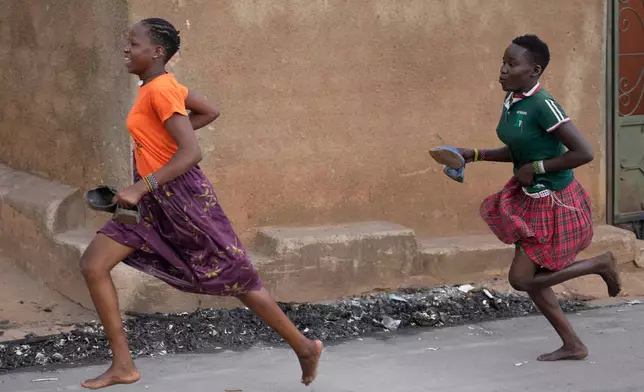 Girls run during protests following the preliminary results in Kampala, Uganda, Friday, Jan. 16, 2026. (AP Photo/Brian Inganga)