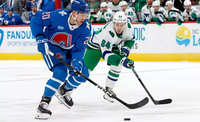 Colorado Avalanche's Ross Colton (20) moves the puck in front of Carolina Hurricanes' Joel Nystrom (64) during the first period of an NHL hockey game in Raleigh, N.C., Saturday, Jan. 3, 2026. (AP Photo/Karl DeBlaker)