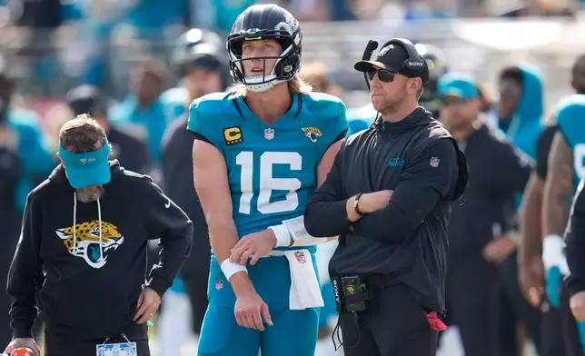 Jacksonville Jaguars quarterback Trevor Lawrence (16) stands next to head coach Liam Coen during the first half of an NFL wild-card playoff football game against the Buffalo Bills Sunday, Jan. 11, 2026, in Jacksonville, Fla. (AP Photo/John Raoux)