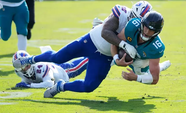 Jacksonville Jaguars quarterback Trevor Lawrence (16) is stopped by Buffalo Bills defensive tackle Daquan Jones (92) on a keeper during the first half of an NFL wild-card playoff football game Sunday, Jan. 11, 2026, in Jacksonville, Fla. (AP Photo/John Raoux)