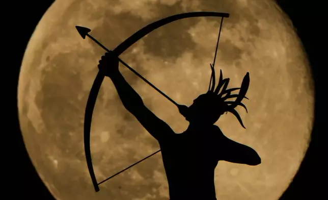 FILE - The full moon rises behind the statue, "Ad Astra," atop the Kansas Statehouse, Saturday, Jan. 3, 2026, in Topeka, Kan. (AP Photo/Charlie Riedel, File)