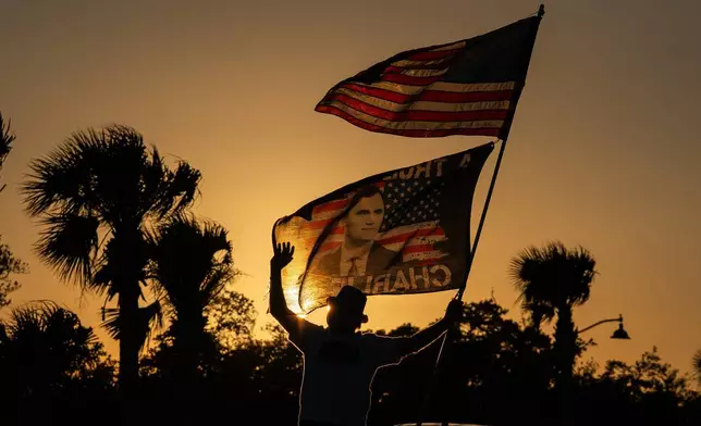 FILE - President Trump supporter Steve Emery holds a flag paying tribute to right-wing political activist Charlie Kirk along a bridge to Mar-A-Lago before President Donald Trump departs West Palm Beach, Fla., for Washington, Sunday, Jan. 4, 2026. (AP Photo/Allison Robbert, File)