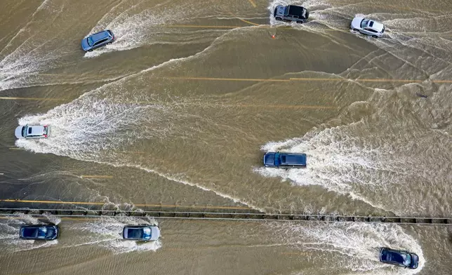 FILE - Cars drive on highway 101 flooded by the "King Tides", occurring when the sun, moon and Earth align, causing a stronger gravitational pull Saturday, Jan. 3, 2026, near Corte Madera in Marin County, Calif. (AP Photo/Ethan Swope, File)