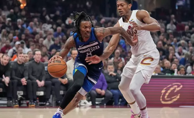 Minnesota Timberwolves guard Bones Hyland, left, drives past Cleveland Cavaliers forward De'andre Hunter, right, in the first half of an NBA basketball game Sunday, Jan. 4, 2026, in Cleveland. (AP Photo/Sue Ogrocki)