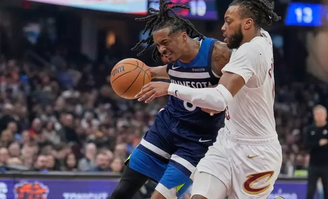 Minnesota Timberwolves guard Bones Hyland (8) drives around Cleveland Cavaliers guard Darius Garland, right, in the half of an NBA basketball game Sunday, Jan. 4, 2026, in Cleveland. (AP Photo/Sue Ogrocki)