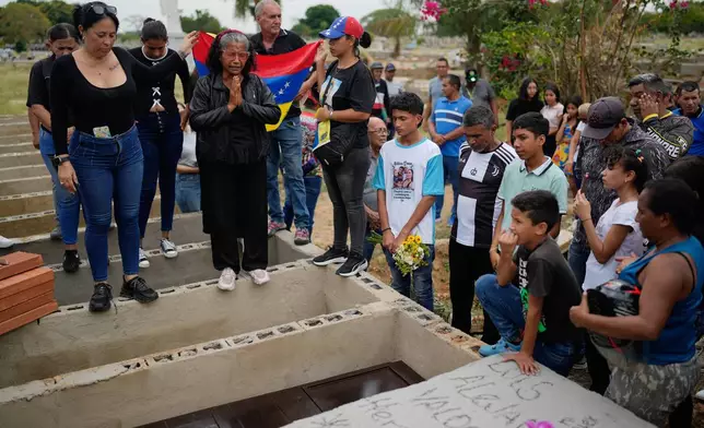 Relatives of Edilson Torres, a Venezuelan police officer who died in prison a month after being arrested on accusations of treason, gather around his grave during his funeral in Guanare, Venezuela, Tuesday, Jan. 13, 2026. (AP Photo/Ariana Cubillos)