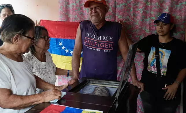 Relatives stand by the coffin of Edilson Torres, a Venezuelan police officer who died in prison a month after being arrested on accusations of treason, in Guanare, Venezuela, Tuesday, Jan. 13, 2026.. (AP Photo/Ariana Cubillos)