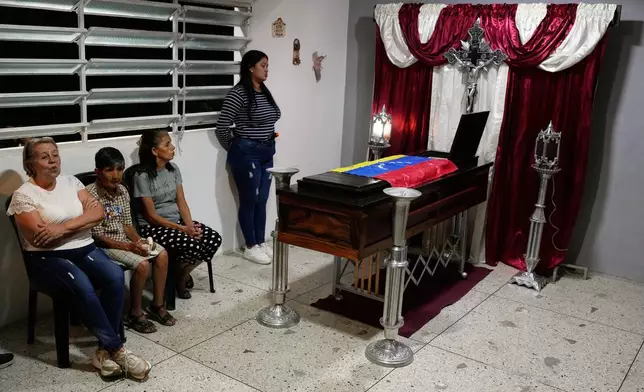 Relatives of Edilson Torres, a Venezuelan police officer who died in prison a month after being arrested on accusations of treason, sit by his coffin during his wake in Guanare, Venezuela, Monday, Jan. 12, 2026. (AP Photo/Ariana Cubillos)