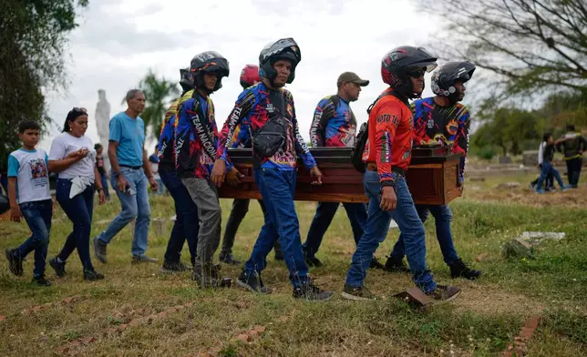 Members of a motorcycle club, friends of Edilson Torres, a Venezuelan police officer who died in prison a month after being arrested on accusations of treason, carry his coffin at a cemetery in Guanare, Venezuela, Tuesday, Jan. 13, 2026. (AP Photo/Ariana Cubillos)