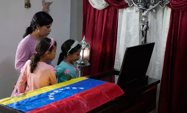 Relatives stand beside the coffin during the wake of Edilson Torres, a Venezuelan police officer who died in prison a month after being arrested on accusations of treason, in Guanare, Venezuela, Tuesday, Jan. 13, 2026. (AP Photo/Ariana Cubillos)