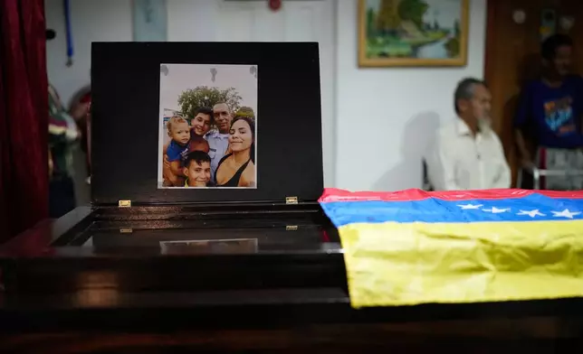 A photo of Edilson Torres, a Venezuelan police officer who died in prison a month after being arrested on accusations of treason, and his family adorns his coffin during his wake at his home in Guanare, Venezuela, Monday, Jan. 12, 2026. (AP Photo/Ariana Cubillos)