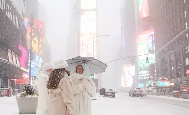 People wait to cross the street in Times Square during a winter storm, Sunday, Jan. 25, 2026, in New York. (AP Photo/Heather Khalifa)