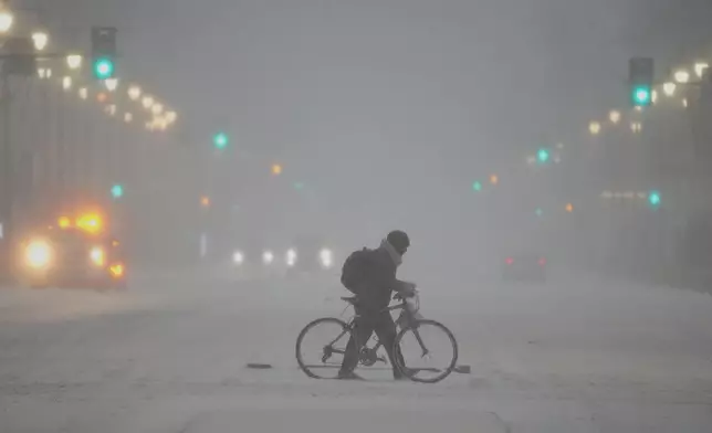 A person pushed a bicycle during a winter storm in Philadelphia, Sunday, Jan. 25, 2026. (AP Photo/Matt Rourke)