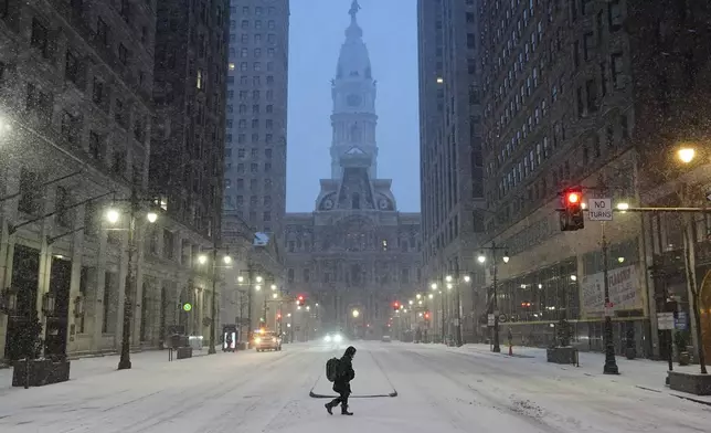 A person walks across a street during a winter storm in Philadelphia, Sunday, Jan. 25, 2026. (AP Photo/Matt Rourke)