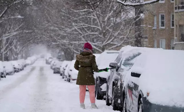 A person cleans the snow from a car during a snowy day in Chicago, Sunday, Jan. 25, 2026. (AP Photo/Nam Y. Huh)