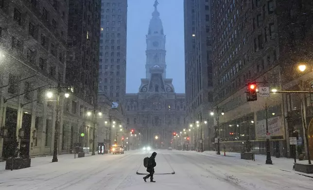 A person walks across a street during a winter storm in Philadelphia, Sunday, Jan. 25, 2026. (AP Photo/Matt Rourke)