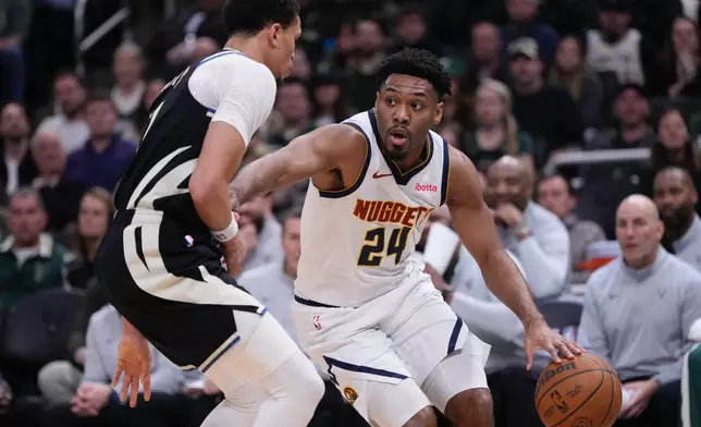 Denver Nuggets' Jalen Pickett tries to get past Milwaukee Bucks' Ryan Rollins during the first half of an NBA basketball game Friday, Jan. 23, 2026, in Milwaukee. (AP Photo/Morry Gash)
