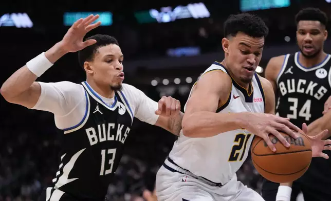 Denver Nuggets' Spencer Jones tries to get past Milwaukee Bucks' Ryan Rollins during the first half of an NBA basketball game Friday, Jan. 23, 2026, in Milwaukee. (AP Photo/Morry Gash)