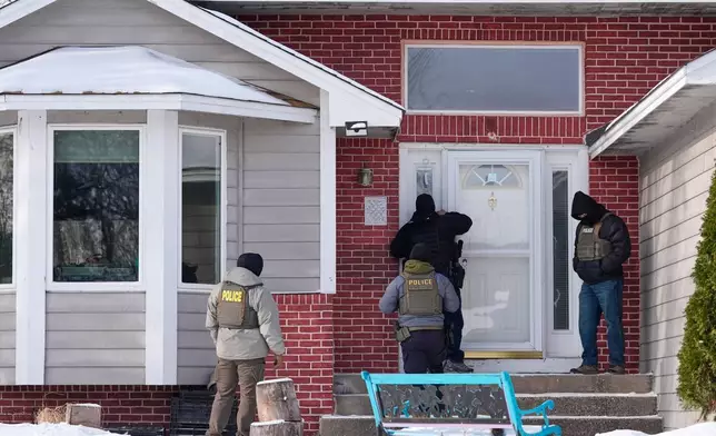 Federal immigration officers look through the window of a home Tuesday, Jan. 20, 2026, in Maplewood, Minn. (AP Photo/Yuki Iwamura)