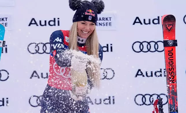 United States' Lindsey Vonn sprays sparkling wine as she celebrates on podium after winning an alpine ski, women's World Cup downhill, in Zauchensee, Austria, Saturday, Jan. 10, 2026. (AP Photo/Giovanni Auletta)