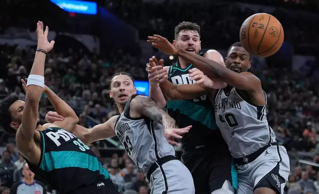 San Antonio Spurs forward Lindy Waters III (43) and forward Harrison Barnes (40) compete with Portland Trail Blazers forward Toumani Camara (33) and center Donovan Clingan (23) for a rebound during the first half of an NBA basketball game in San Antonio, Saturday, Jan. 3, 2026. (AP Photo/Eric Gay)