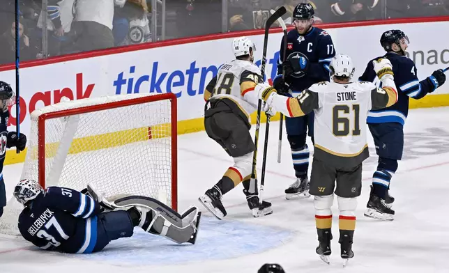 Vegas Golden Knights' Tomas Hertl (48) celebrates his game-winning goal in overtime against Winnipeg Jets goaltender Connor Hellebuyck (37) with Mark Stone (61) during their NHL hockey game in Winnipeg, Tuesday Jan. 6, 2026. (Fred Greenslade/The Canadian Press via AP)