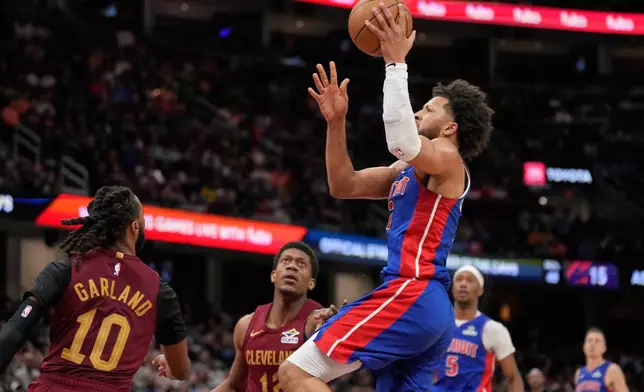 Detroit Pistons guard Cade Cunningham shoots between Cleveland Cavaliers guard Darius Garland (10) and forward De'andre Hunter (12) in the second half of an NBA basketball game Sunday, Jan. 4, 2026, in Cleveland. (AP Photo/Sue Ogrocki)