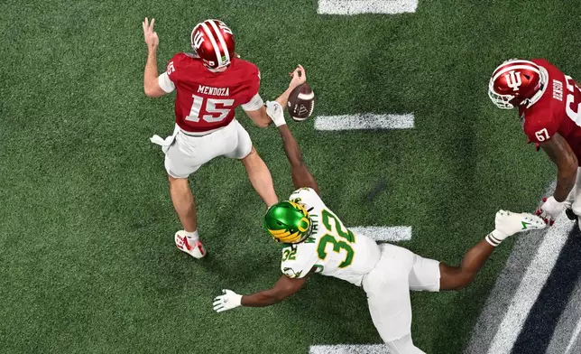 Oregon linebacker Nasir Wyatt (32) strips the ball from Indiana quarterback Fernando Mendoza (15) during the first half of the Peach Bowl NCAA college football playoff semifinal, Friday, Jan. 9, 2026, in Atlanta. (AP Photo/Danny Karnik)