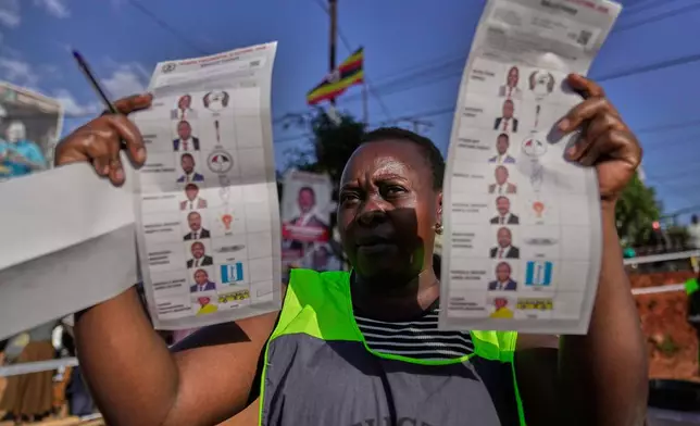 An election official holds up unmarked ballots during the vote count after polls closed for the presidential election, at a polling center in Kampala, Uganda, Thursday, Jan. 15, 2026. (AP Photo/Brian Inganga)