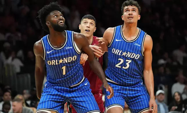 Miami Heat forward Simone Fontecchio (0) is pushed back by Orlando Magic forwards Jonathan Isaac (1) and Tristan da Silva (23) during the second half of an NBA basketball game Wednesday, Jan. 28, 2026, in Miami. (AP Photo/Marta Lavandier)
