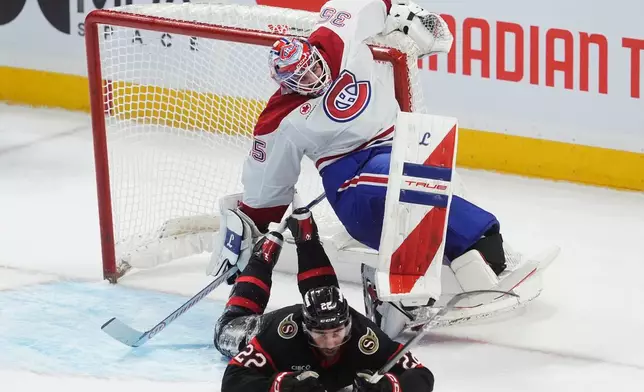 Montreal Canadiens goaltender Samuel Montembeault (35) grabs the net as Ottawa Senators right wing Michael Amadio (22) slides into him during the second period of an NHL hockey game, in Ottawa, Ontario, Saturday, Jan. 17, 2026. (Adrian Wyld/The Canadian Press via AP)