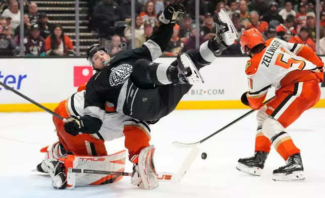 Los Angeles Kings left wing Warren Foegele, center, falls over Anaheim Ducks goaltender Ville Husso, left, as defenseman Olen Zellweger takes the puck during the second period of an NHL hockey game Saturday, Jan. 17, 2026, in Anaheim, Calif. (AP Photo/Mark J. Terrill)