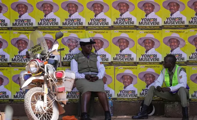 Traffic police officers sit in front of campaign posters of President Yoweri Museveni, the National Resistance Movement (NRM) presidential candidate, during the general election, in Kampala, Uganda, Thursday, Jan. 15, 2026. (AP Photo/Brian Inganga)