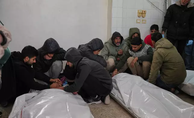 Palestinians mourn over the bodies of people who were killed in an Israeli strike, before their funeral at Al-Aqsa Hospital in Deir al-Balah, central Gaza Strip, Friday, Jan. 30, 2026. (AP Photo/Abdel Kareem Hana)
