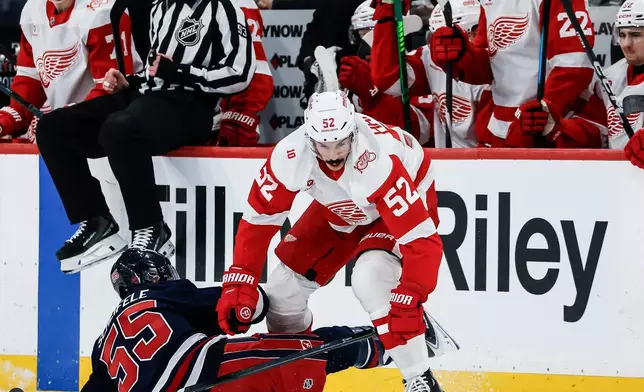 Detroit Red Wings' Travis Hamonic (52) collides with Winnipeg Jets' Mark Scheifele (55) during second-period NHL hockey game action in Winnipeg, Manitoba, Saturday, Jan. 24, 2026. (John Woods/The Canadian Press via AP)