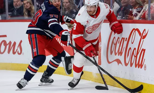 Detroit Red Wings' Ben Chiarot (8) battles for the puck with Winnipeg Jets' Tanner Pearson (70) during the second period of an NHL game in Winnipeg, Saturday, Jan. 24, 2026. (John Woods/The Canadian Press via AP)