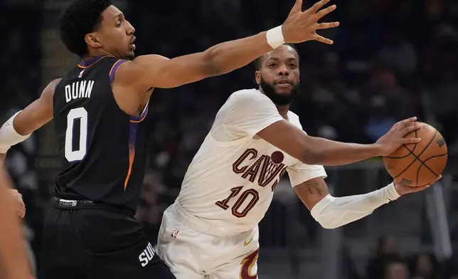 Cleveland Cavaliers guard Darius Garland (10) passes around Phoenix Suns forward Ryan Dunn (0) in the first half of an NBA basketball game Wednesday, Dec. 31, 2025, in Cleveland. (AP Photo/Sue Ogrocki)