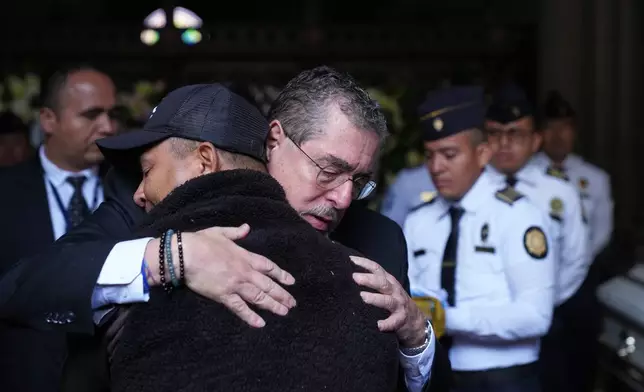 Guatemalan President Bernardo Arevalo comforts the relative of one of the police officers killed while retaking control of three prisons, during the wake for the officers at the Interior Ministry in Guatemala City, Monday, Jan. 19, 2026. (AP Photo/Moises Castillo)