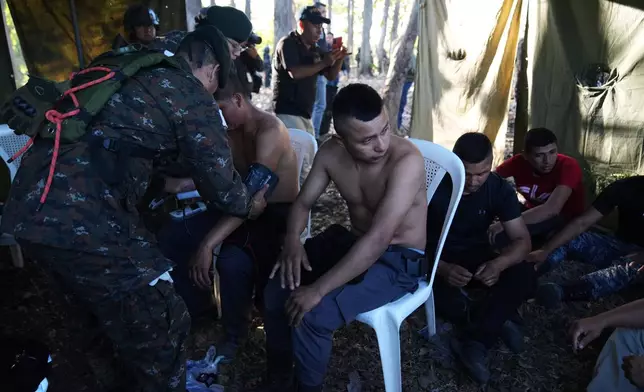 A medic checks on freed prison guards outside the Renovation maximum-security prison after security forces entered the facility to retake control in Escuintla, Guatemala, Sunday, Jan. 18, 2026. (AP Photo/Moises Castillo)