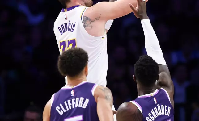 Los Angeles Lakers guard Luka Doncic, back center, shoots as Sacramento Kings guard Nique Clifford (5) and guard Dennis Schroder (17) watch during the second half of an NBA basketball game, Sunday, Dec. 28, 2025, in Los Angeles. (AP Photo/Jessie Alcheh)