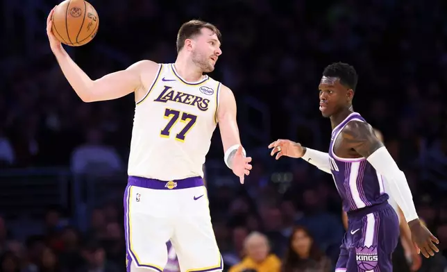 Los Angeles Lakers guard Luka Doncic (77) shields the ball from Sacramento Kings guard Dennis Schroder, right, during the second half of an NBA basketball game, Sunday, Dec. 28, 2025, in Los Angeles. (AP Photo/Jessie Alcheh)