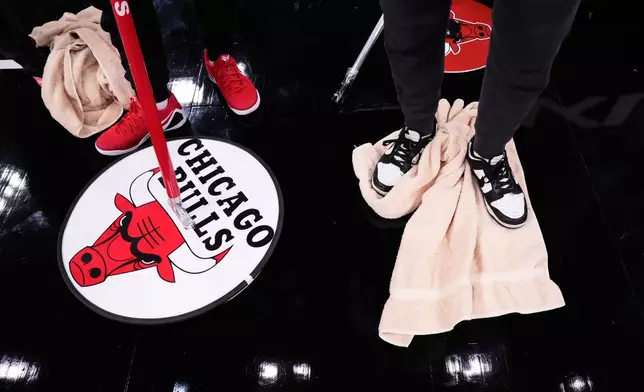 United Center employees try to dry the court before an NBA basketball game between the Miami Heat and the Chicago Bulls in Chicago, Thursday, Jan. 8, 2026. (AP Photo/Nam Y. Huh)