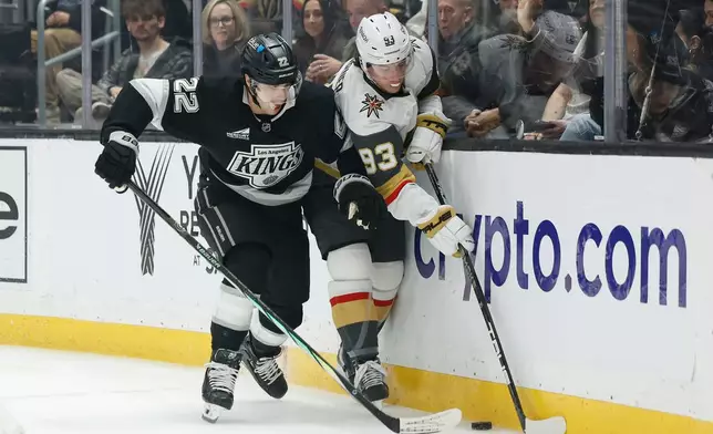 Los Angeles Kings left wing Kevin Fiala (22) and Vegas Golden Knights right wing Mitch Marner (93) fight for possession of the puck during the first period of an NHL hockey game Wednesday, Jan. 14, 2026, in Los Angeles. (AP Photo/Caroline Brehman)