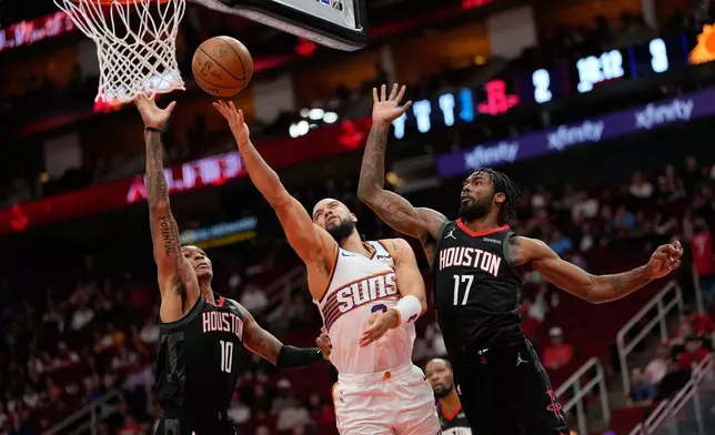 Phoenix Suns' Dillon Brooks, center, goes up for a shot as Houston Rockets' Jabari Smith Jr. (10) and Tari Eason (17) defend during the first half of an NBA basketball game Monday, Jan. 5, 2026, in Houston. (AP Photo/David J. Phillip)