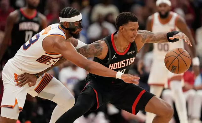 Phoenix Suns' Jordan Goodwin, left, reaches to knock the ball away from Houston Rockets' Jabari Smith Jr. during the first half of an NBA basketball game Monday, Jan. 5, 2026, in Houston. (AP Photo/David J. Phillip)