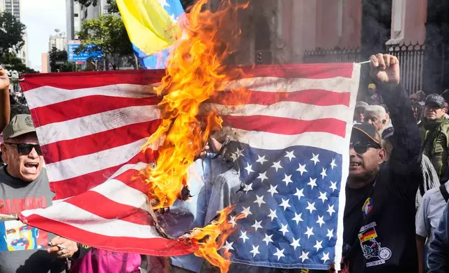 Government supporters burn a U.S. flag in Caracas, Venezuela, Saturday, Jan. 3, 2026, after U.S. President Donald Trump announced that U.S. forces had captured Venezuelan President Nicolás Maduro and his wife. (AP Photo/Ariana Cubillos)